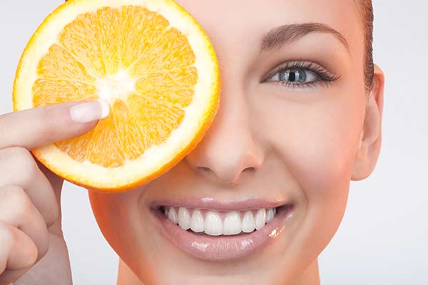 angeschnittene Orange vor dem Gesicht einer Frau